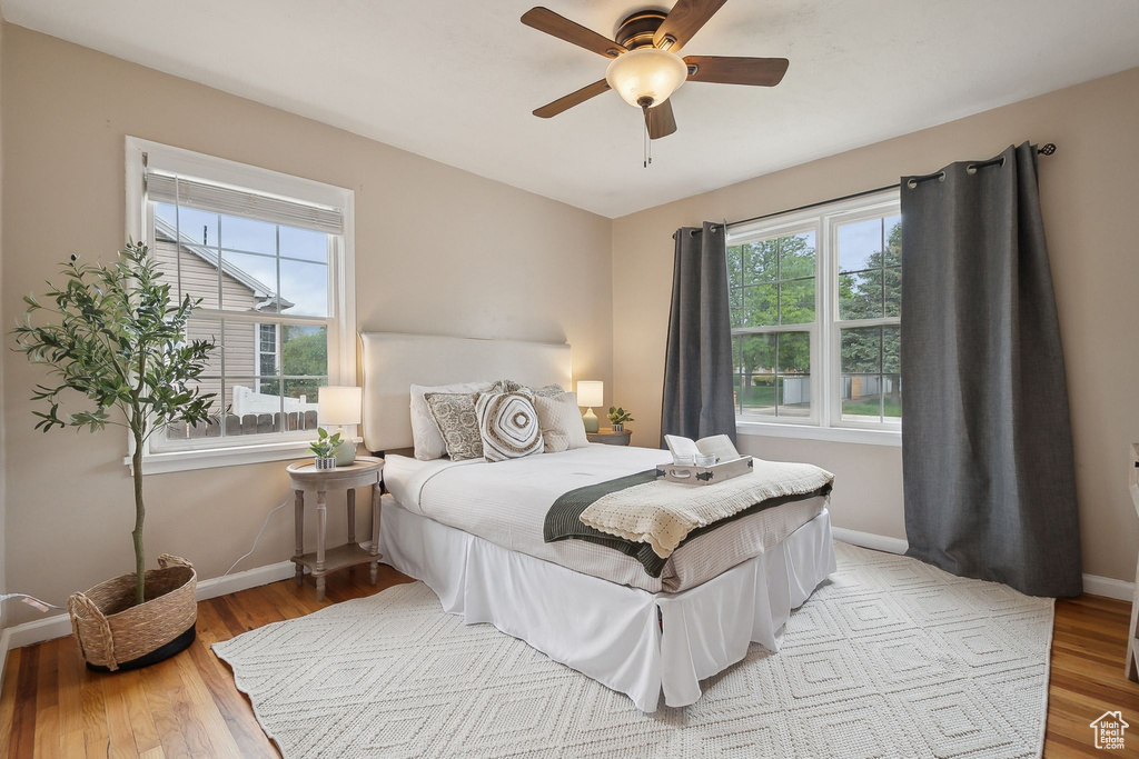 Bedroom featuring multiple windows, baseboards, light wood-type flooring, and ceiling fan