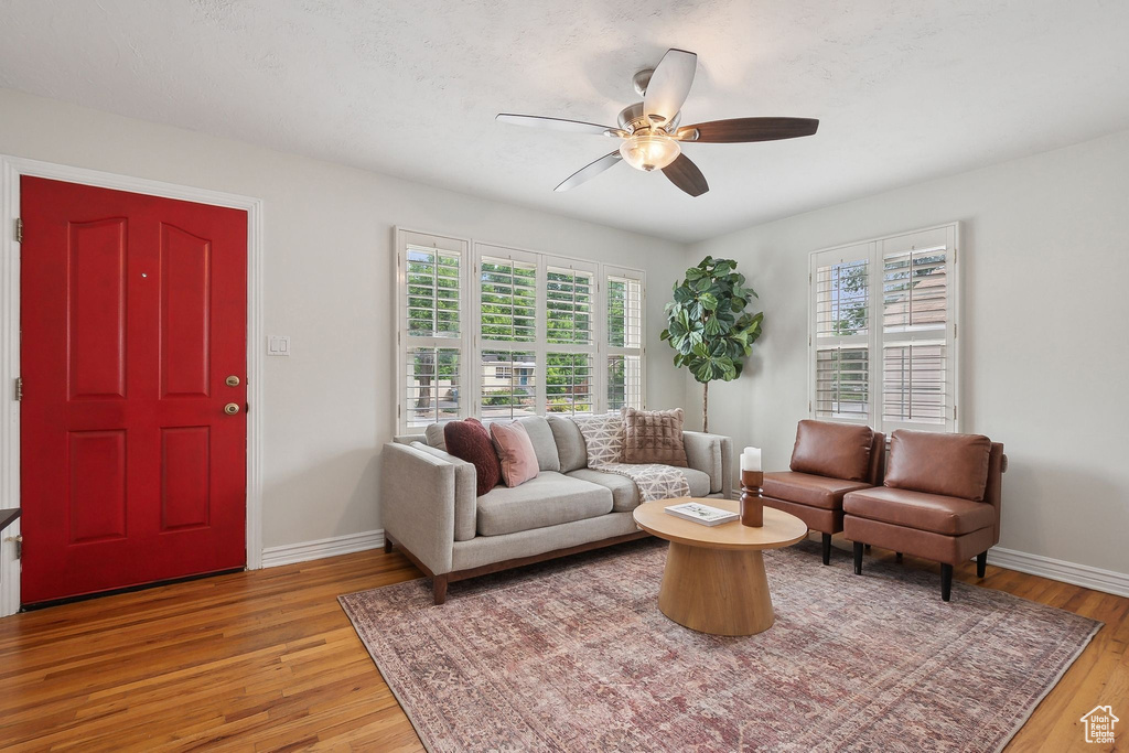 Living room with ceiling fan, light wood-type flooring, and baseboards