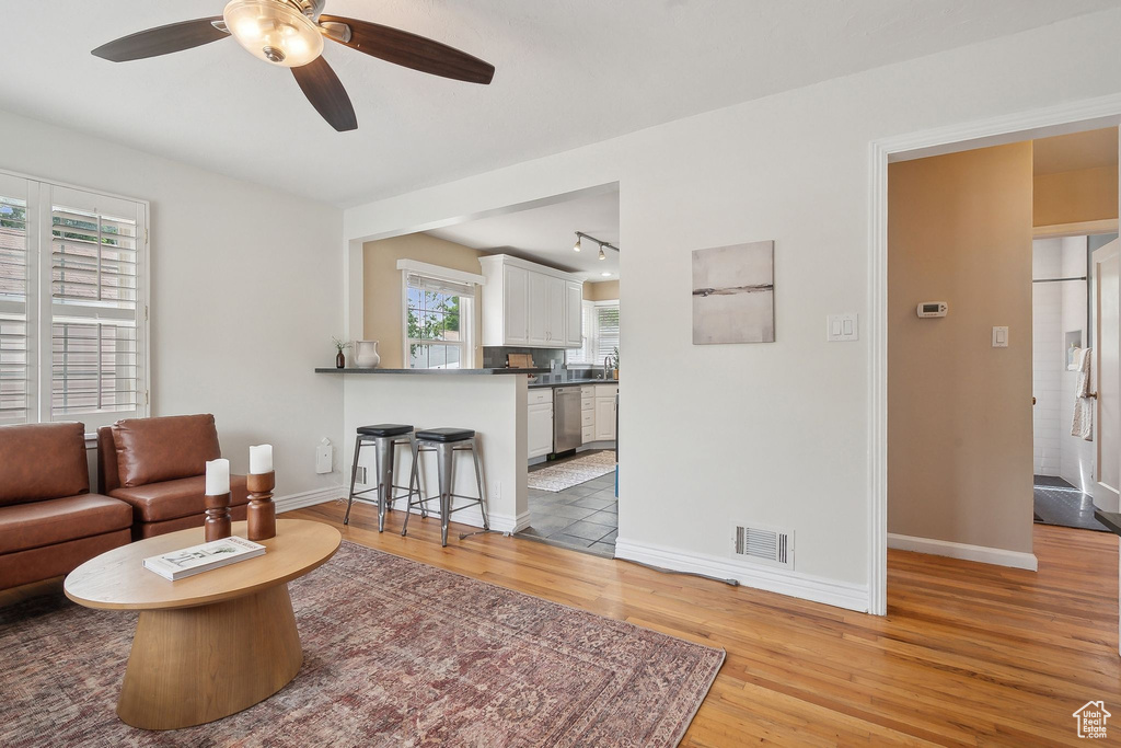 Living room featuring light wood-style flooring, track lighting, a ceiling fan, and baseboards