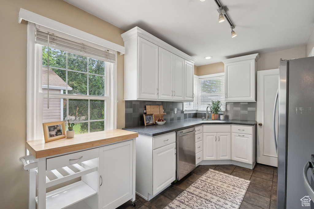 Kitchen with stainless steel appliances, a sink, healthy amount of natural light, and white cabinetry
