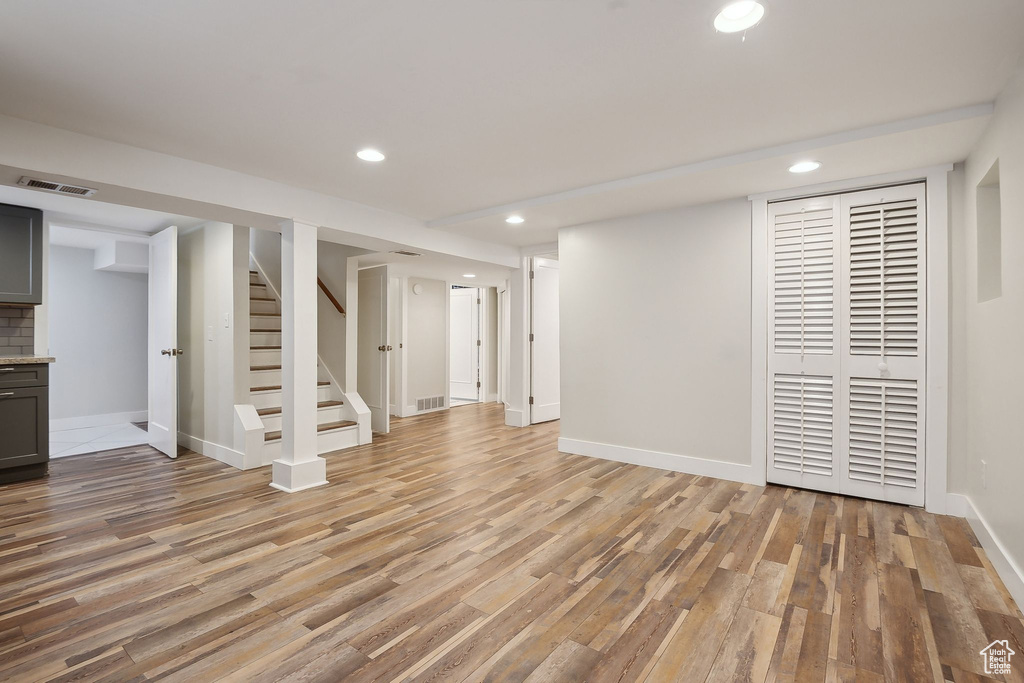 Finished basement with light wood-type flooring, recessed lighting, baseboards, and stairs
