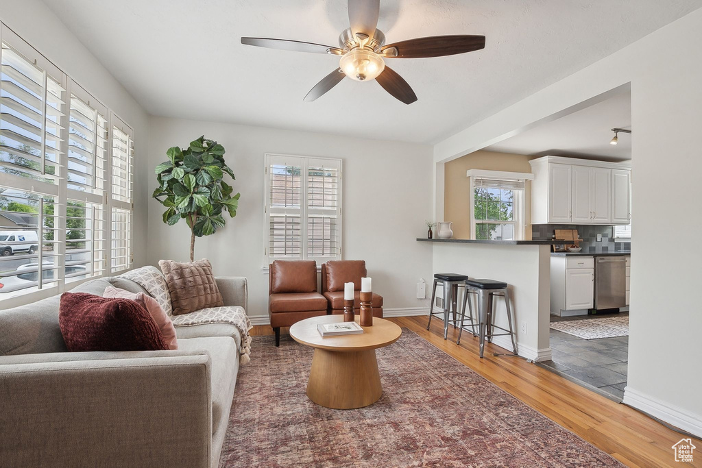 Living room with a ceiling fan, wood finished floors, and baseboards