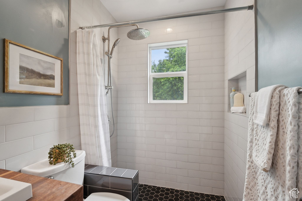 Full bathroom featuring tiled shower, toilet, tile walls, and vanity