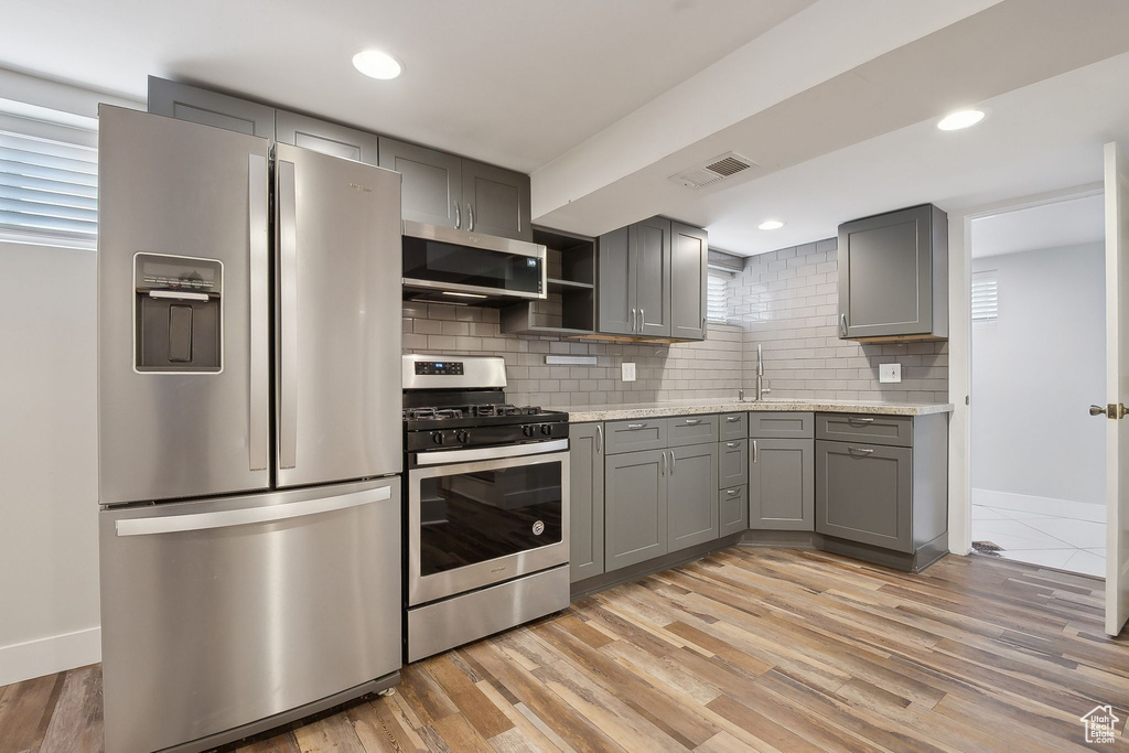 Kitchen with stainless steel appliances, gray cabinetry, baseboards, decorative backsplash, and recessed lighting