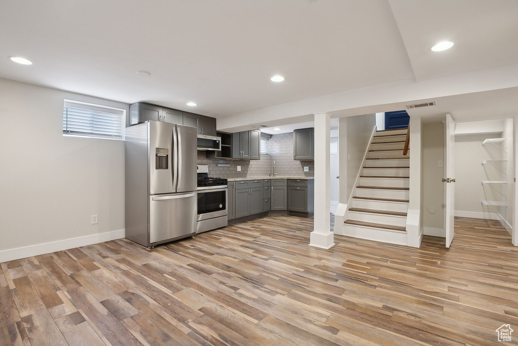 Kitchen with stainless steel appliances, gray cabinetry, ventilation hood, light wood finished floors, and recessed lighting