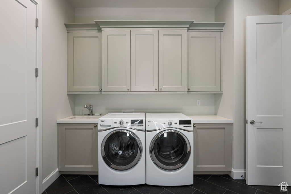 Laundry room with cabinet space, dark tile patterned flooring, washer and dryer, and baseboards