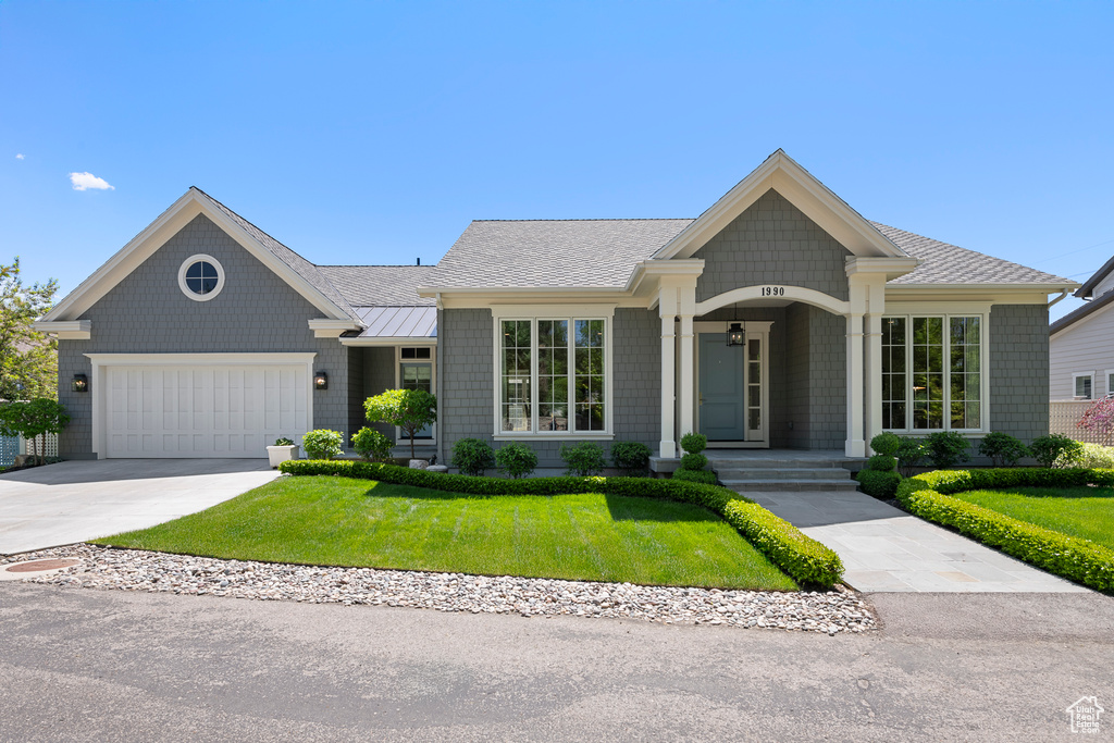 Single story home featuring a front lawn, a standing seam roof, an attached garage, concrete driveway, and metal roof