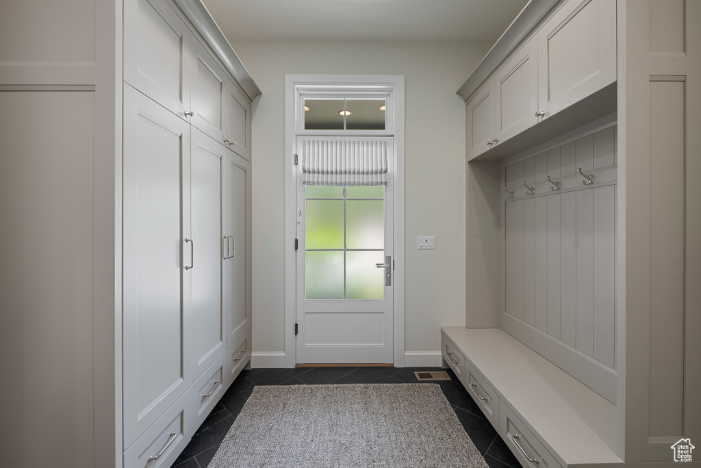 Mudroom featuring dark tile patterned floors and baseboards