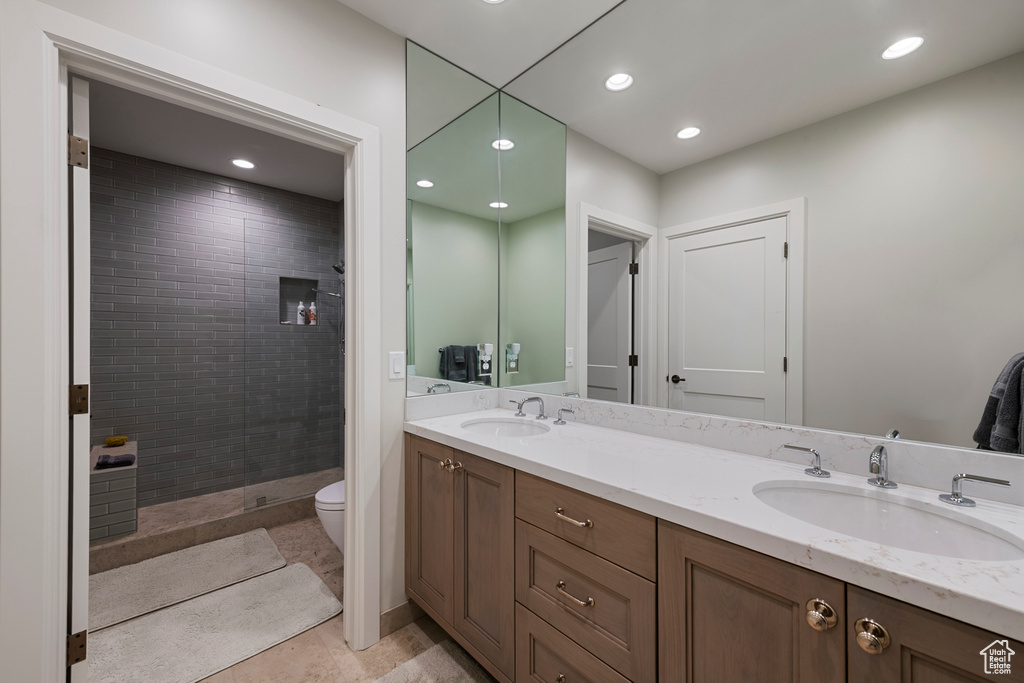 Full bathroom featuring a tile shower, double vanity, recessed lighting, toilet, and tile patterned flooring