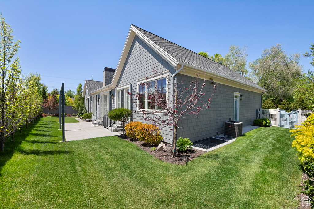 View of property exterior with a patio, central AC, roof with shingles, and entry steps