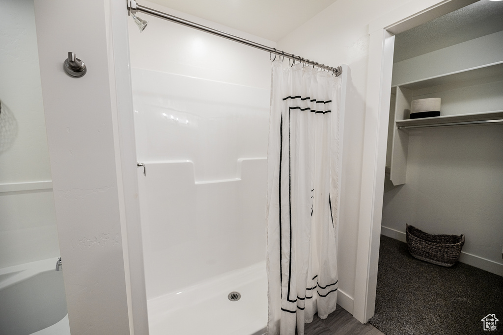 Full bath with a shower stall and baseboards