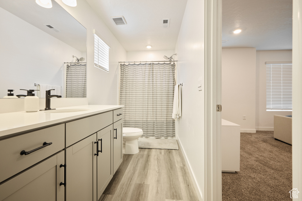 Full bathroom featuring toilet, a shower with shower curtain, vanity, wood finished floors, and baseboards