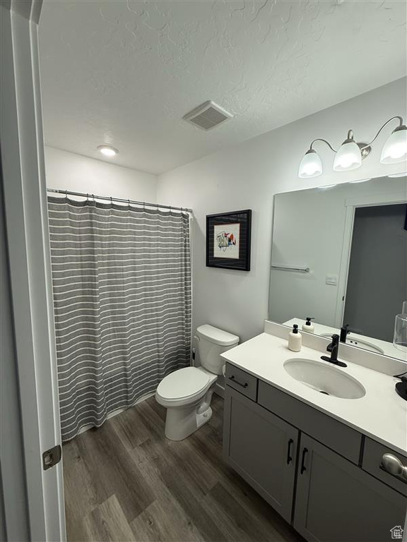 Bathroom featuring wood finished floors, vanity, toilet, a textured ceiling, and a shower with curtain