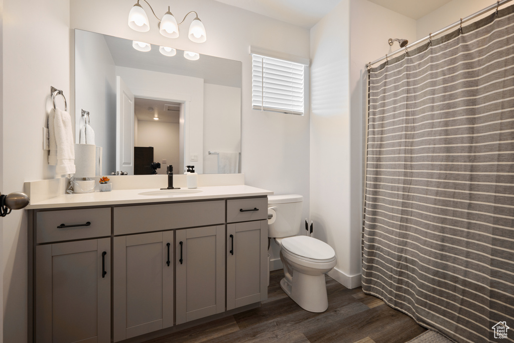 Bathroom featuring wood finished floors, vanity, toilet, and curtained shower