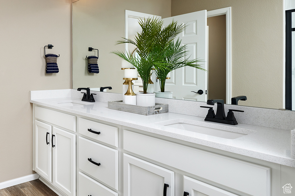 Full bathroom with double vanity, wood finished floors, and baseboards