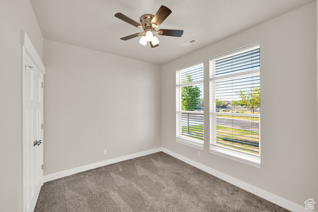 Carpeted empty room featuring baseboards and a ceiling fan