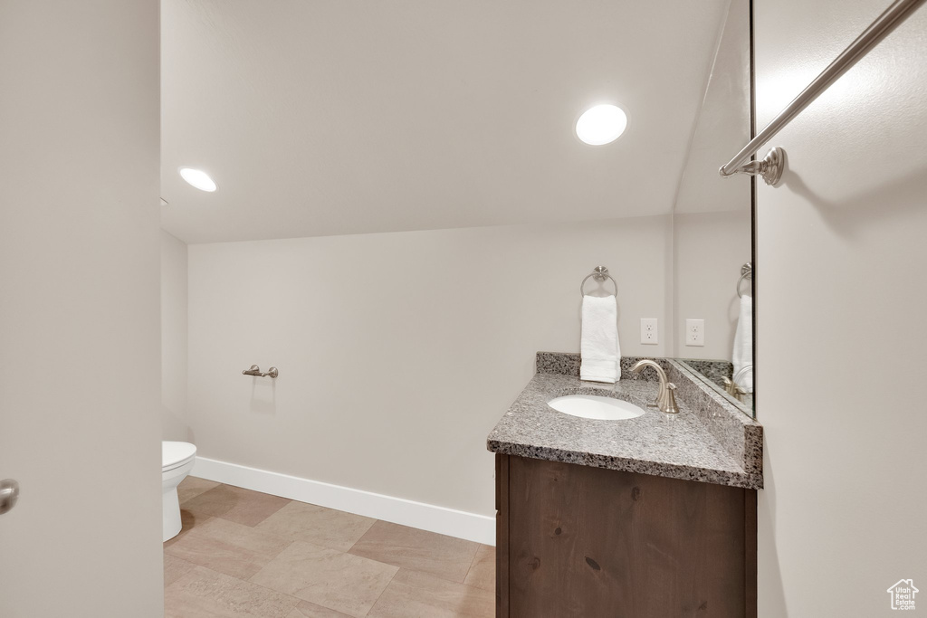 Bathroom featuring vanity, toilet, and baseboards