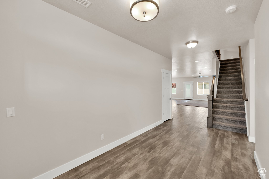 Unfurnished room featuring baseboards, stairway, dark wood-style floors, and a smoke detector
