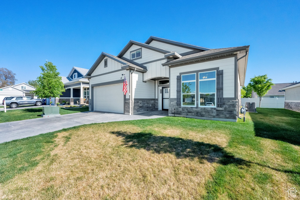 Craftsman house featuring stone siding, driveway, a garage, and board and batten siding