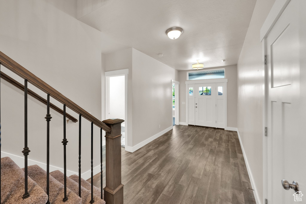 Entryway featuring dark wood-style floors, baseboards, and stairs