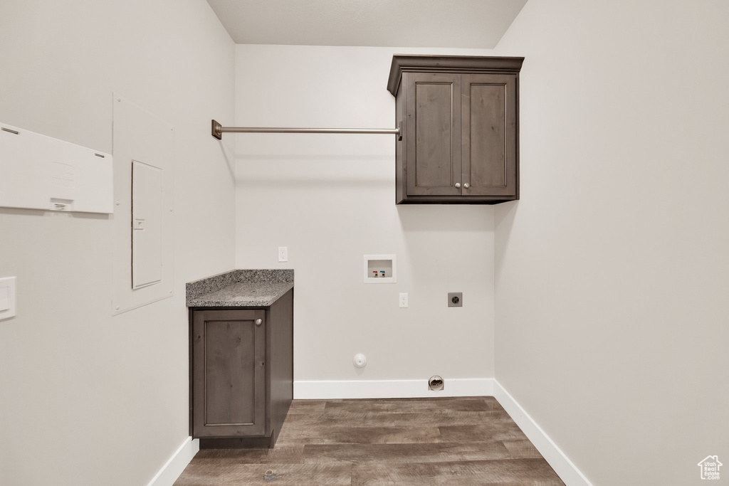 Washroom featuring electric dryer hookup, dark wood-type flooring, hookup for a washing machine, baseboards, and cabinet space