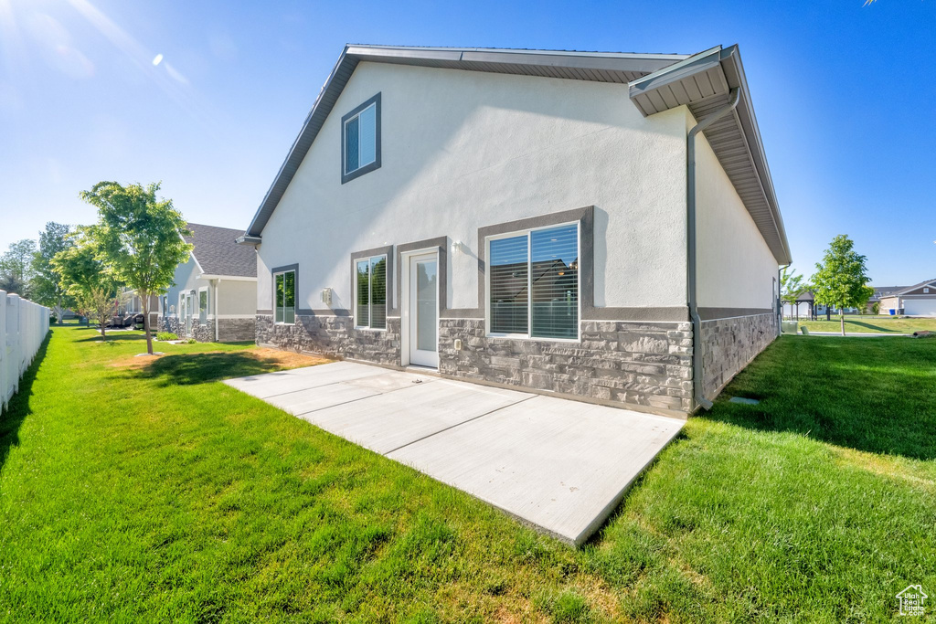 Rear view of house with stucco siding, a patio, and stone siding