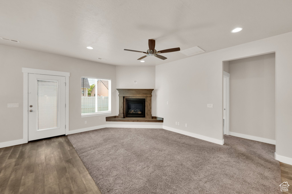 Unfurnished living room with baseboards, recessed lighting, ceiling fan, a glass covered fireplace, and wood finished floors