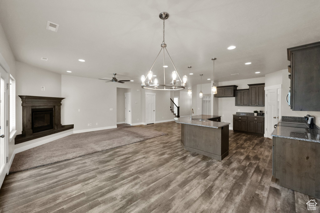 Kitchen with a sink, light stone counters, dark wood finished floors, recessed lighting, and dark brown cabinetry