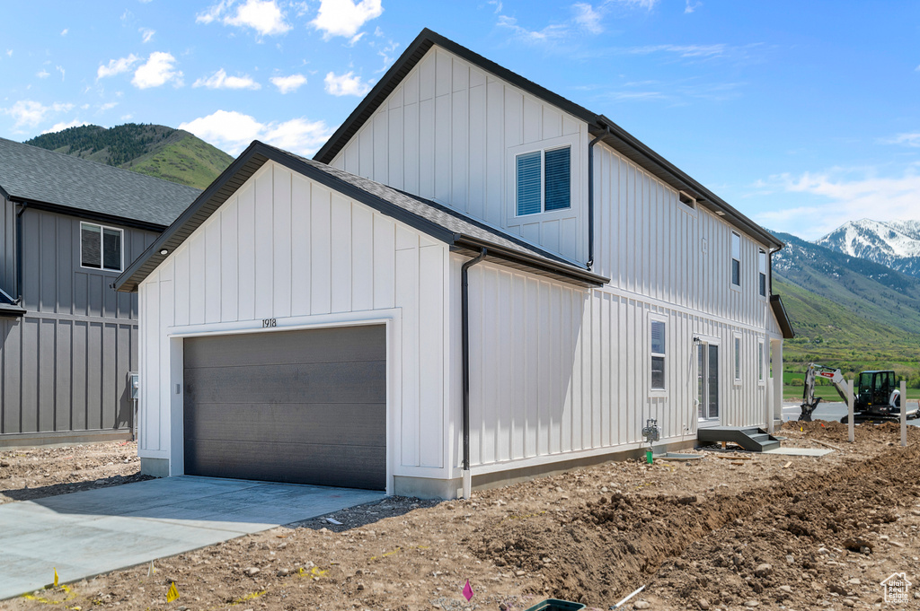 View of home's exterior with a mountain view, a garage, concrete driveway, and board and batten siding