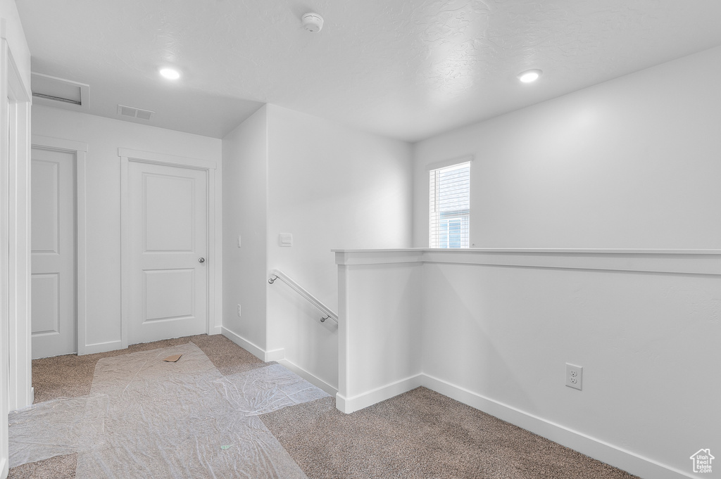 Hall with carpet flooring, an upstairs landing, recessed lighting, baseboards, and attic access