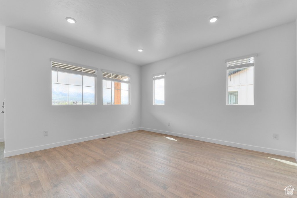 Empty room featuring light wood-type flooring, baseboards, and recessed lighting