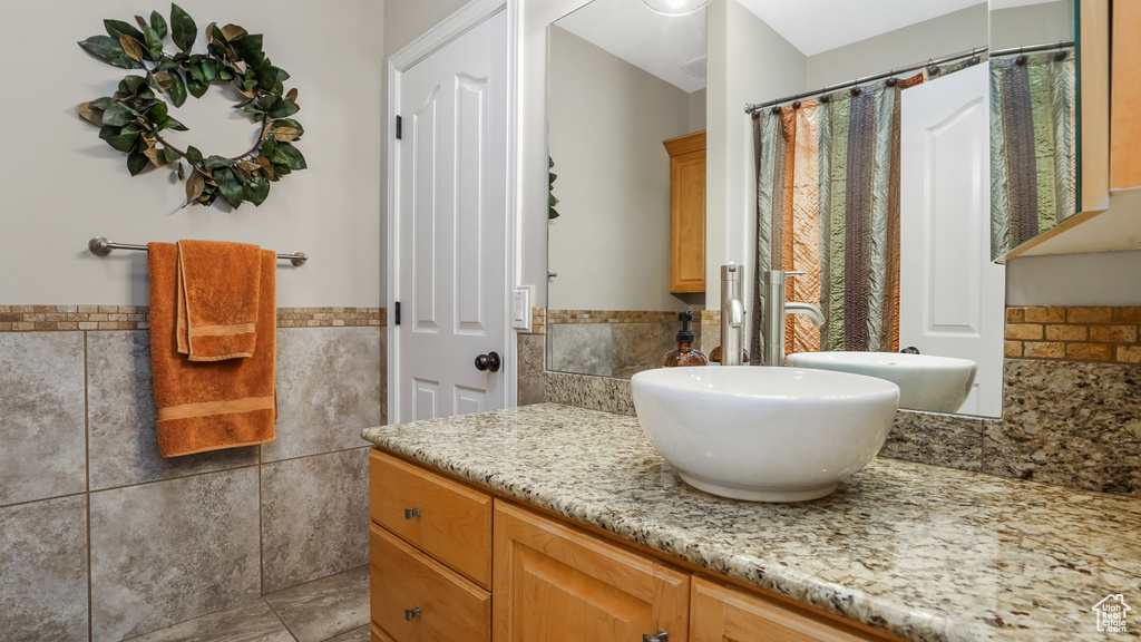 Full bath featuring tile walls, vanity, a wainscoted wall, and a shower with shower curtain