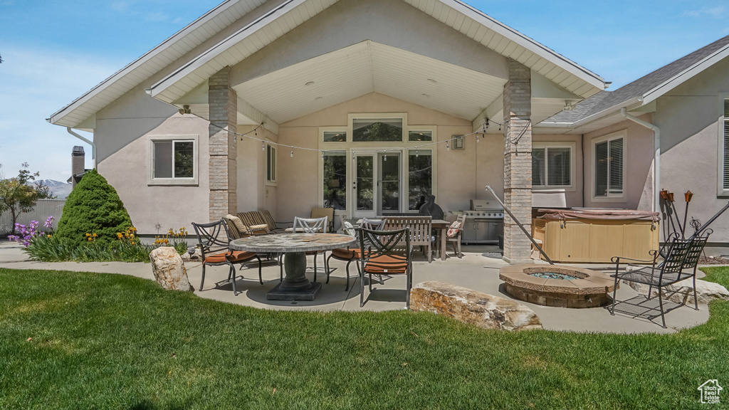 Rear view of property with a hot tub, a patio, and stucco siding