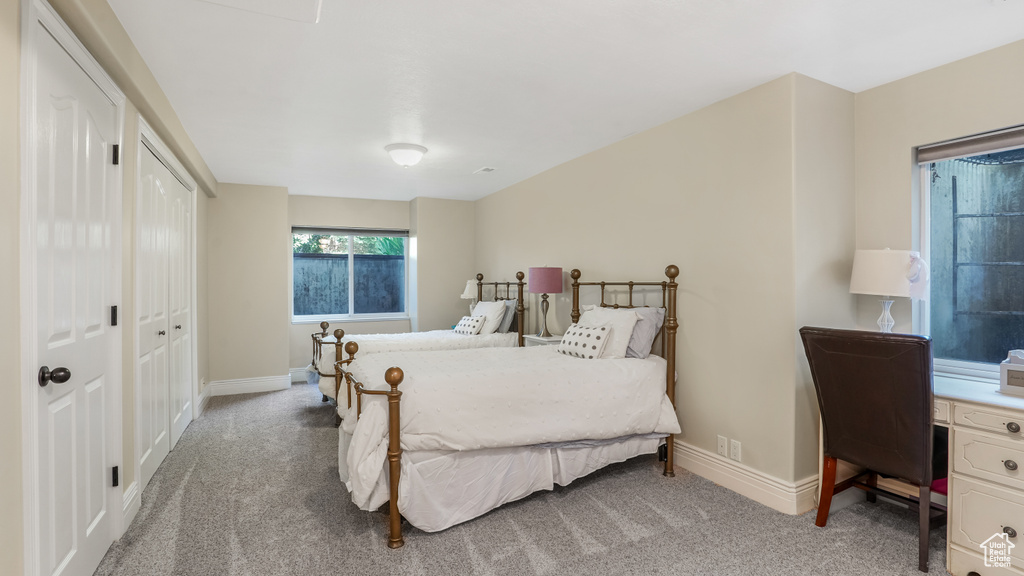Bedroom with light colored carpet, baseboards, and a closet