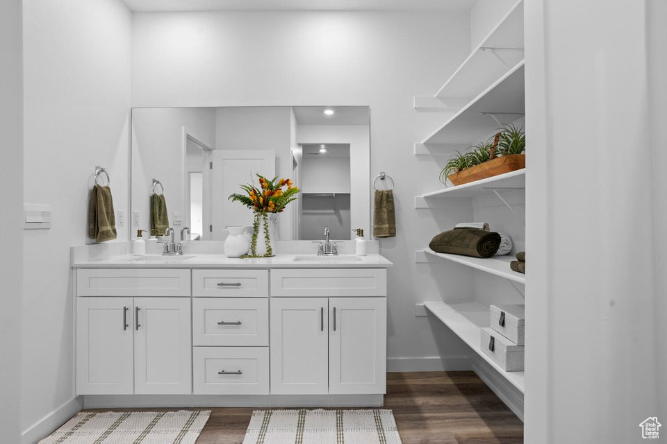 Bathroom with baseboards, double vanity, and wood finished floors