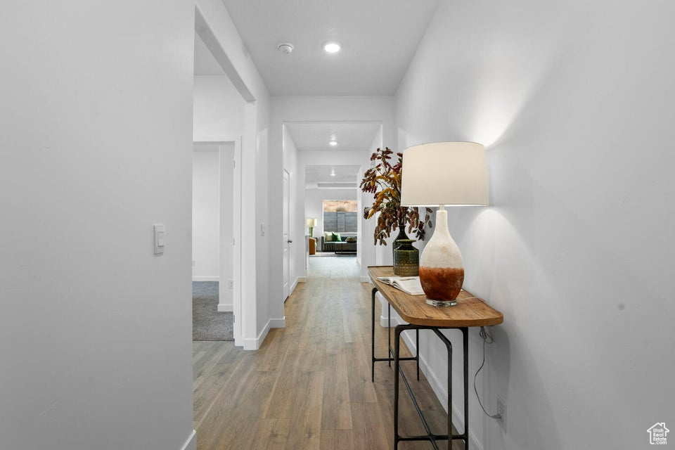 Corridor featuring baseboards, light wood finished floors, and recessed lighting