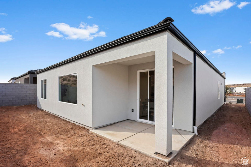 Rear view of house featuring a patio, fence, and stucco siding