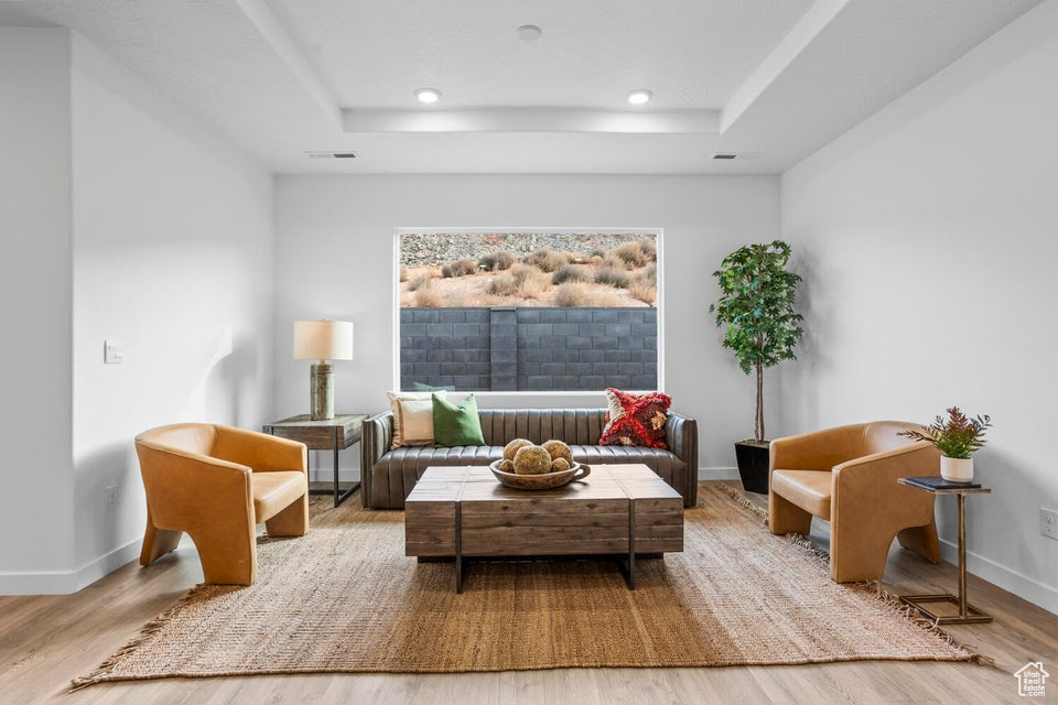 Living room with wood finished floors, recessed lighting, baseboards, and a raised ceiling
