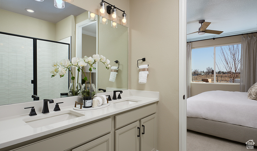 Bathroom featuring ceiling fan, double vanity, and a tile shower