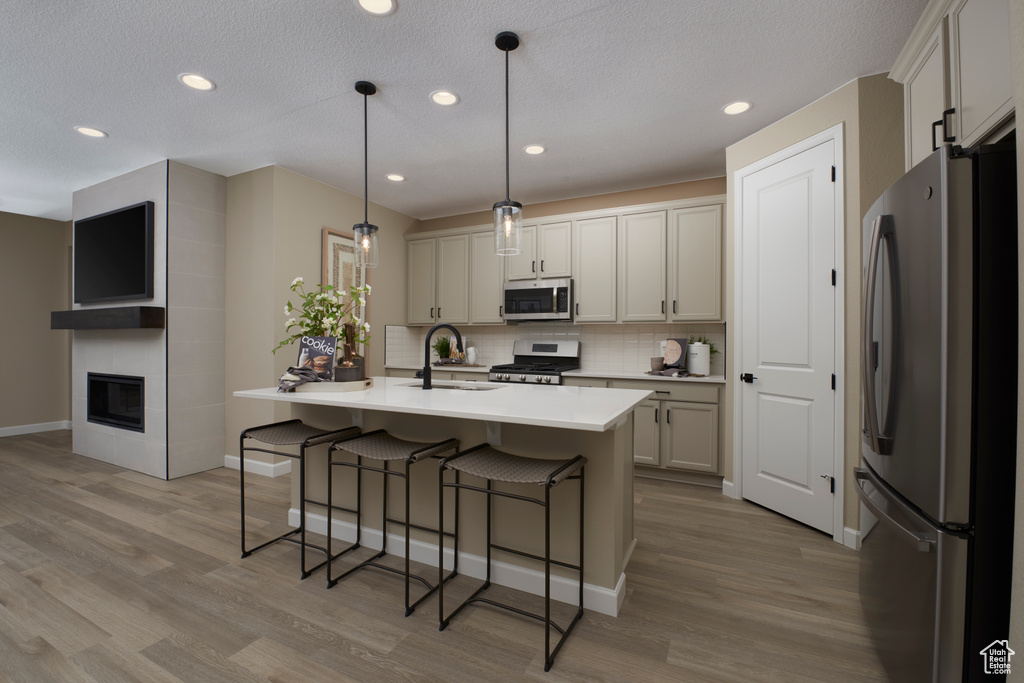 Kitchen with stainless steel appliances, a sink, tasteful backsplash, a breakfast bar area, and wood finished floors