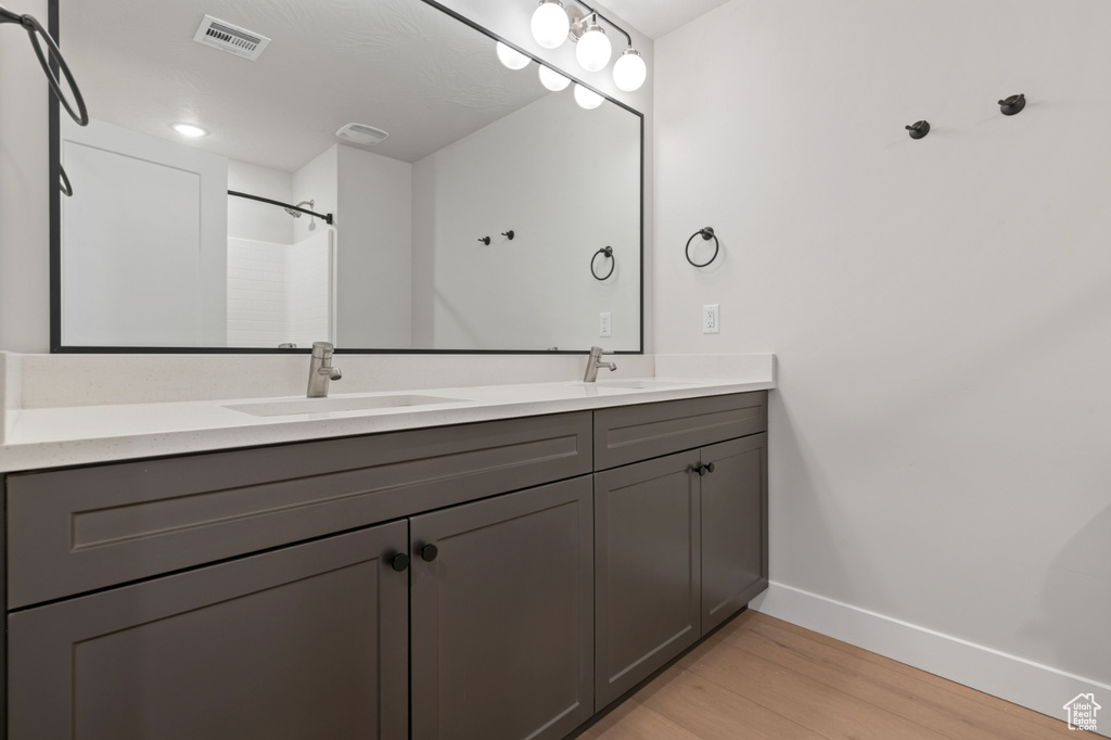 Full bath with baseboards, wood finished floors, and double vanity