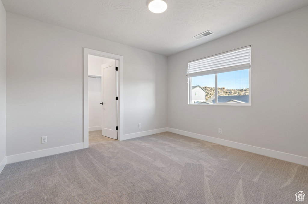 Unfurnished room featuring light carpet and baseboards