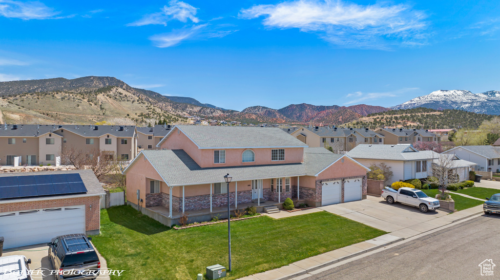 View of front facade featuring covered porch, a residential view, a mountain view, and a garage