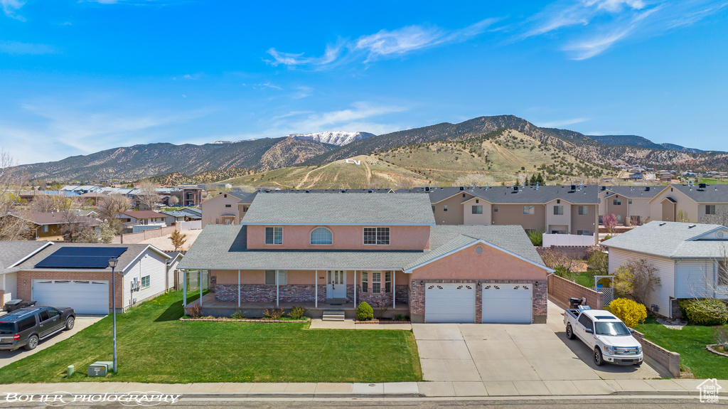Traditional-style house featuring a residential view, covered porch, a garage, concrete driveway, and a mountain view