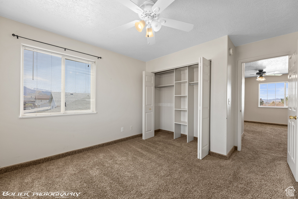 Unfurnished bedroom featuring carpet floors, a textured ceiling, baseboards, a closet, and ceiling fan