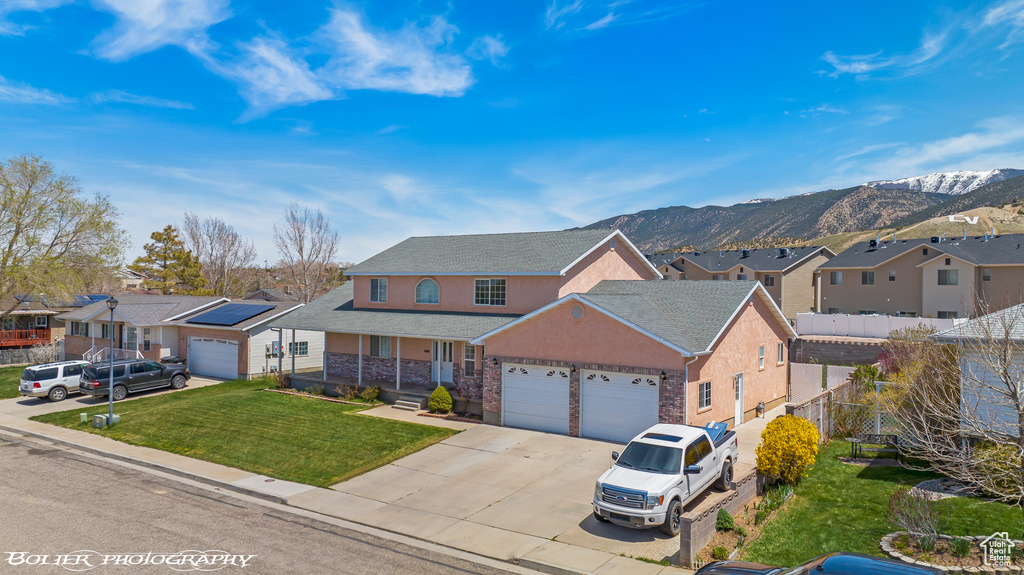 Traditional-style house featuring a residential view, a garage, concrete driveway, covered porch, and a mountain view