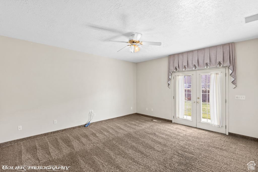 Carpeted spare room with a ceiling fan, french doors, a textured ceiling, and baseboards