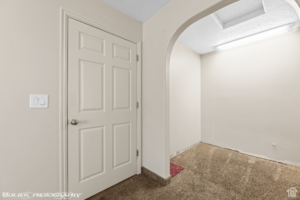 Hallway featuring carpet floors, a textured ceiling, and arched walkways