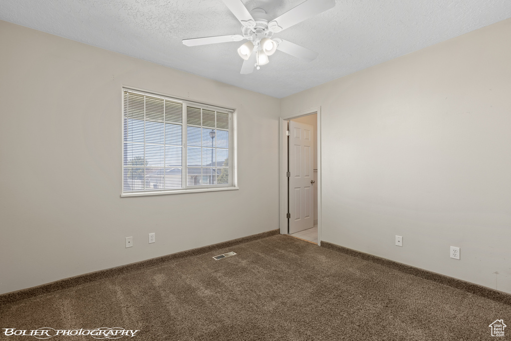 Empty room with carpet flooring, a ceiling fan, a textured ceiling, and baseboards