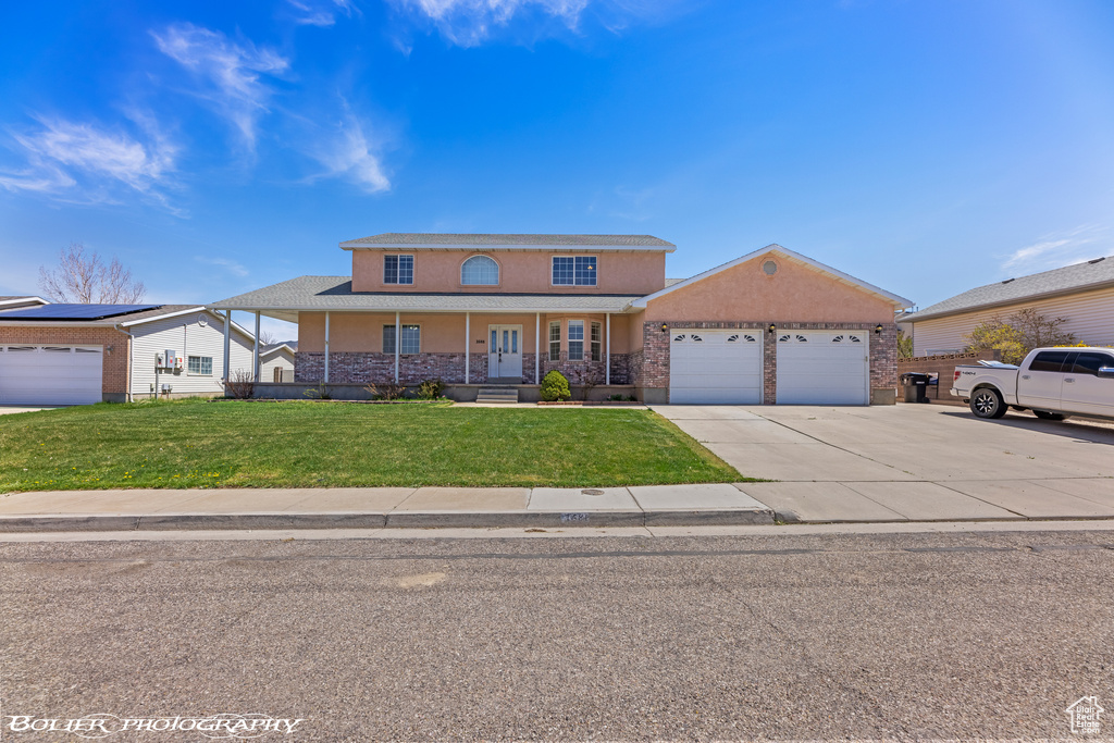 View of front of house with an attached garage, a front yard, concrete driveway, stucco siding, and a porch